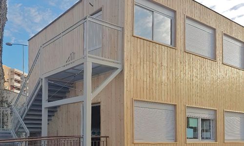Scuola su due piani realizzata con moduli prefabbricati rivestiti in legno con scala di sicurezza esterna